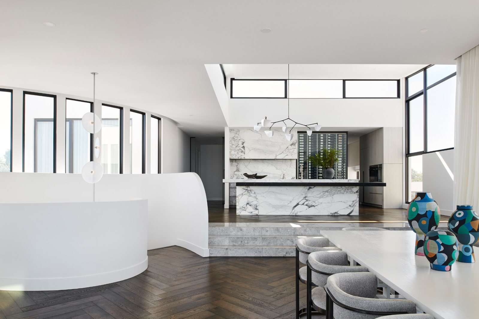 Brighton, Beach Road kitchen with a veined stone island and splashback beyond the dining table