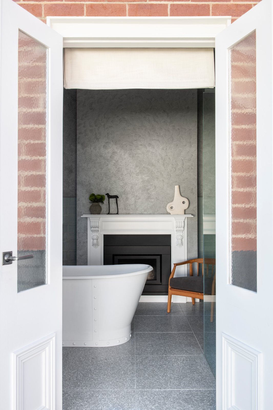 Camberwell Mews bathroom with a freestanding bath, seen through double doors in a brick wall