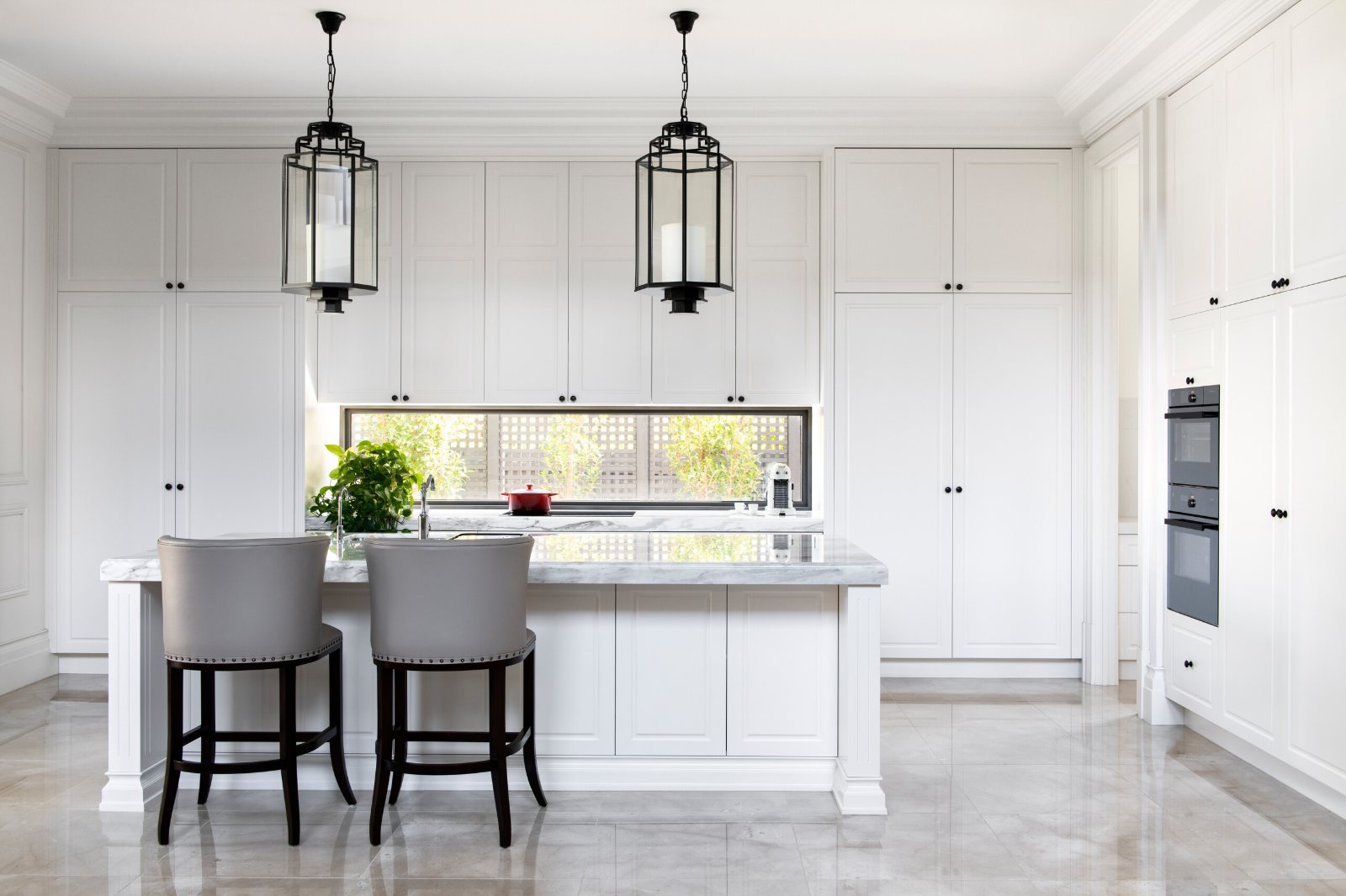Kew, Alfred Street kitchen with white cabinetry, an island and two lantern pendants