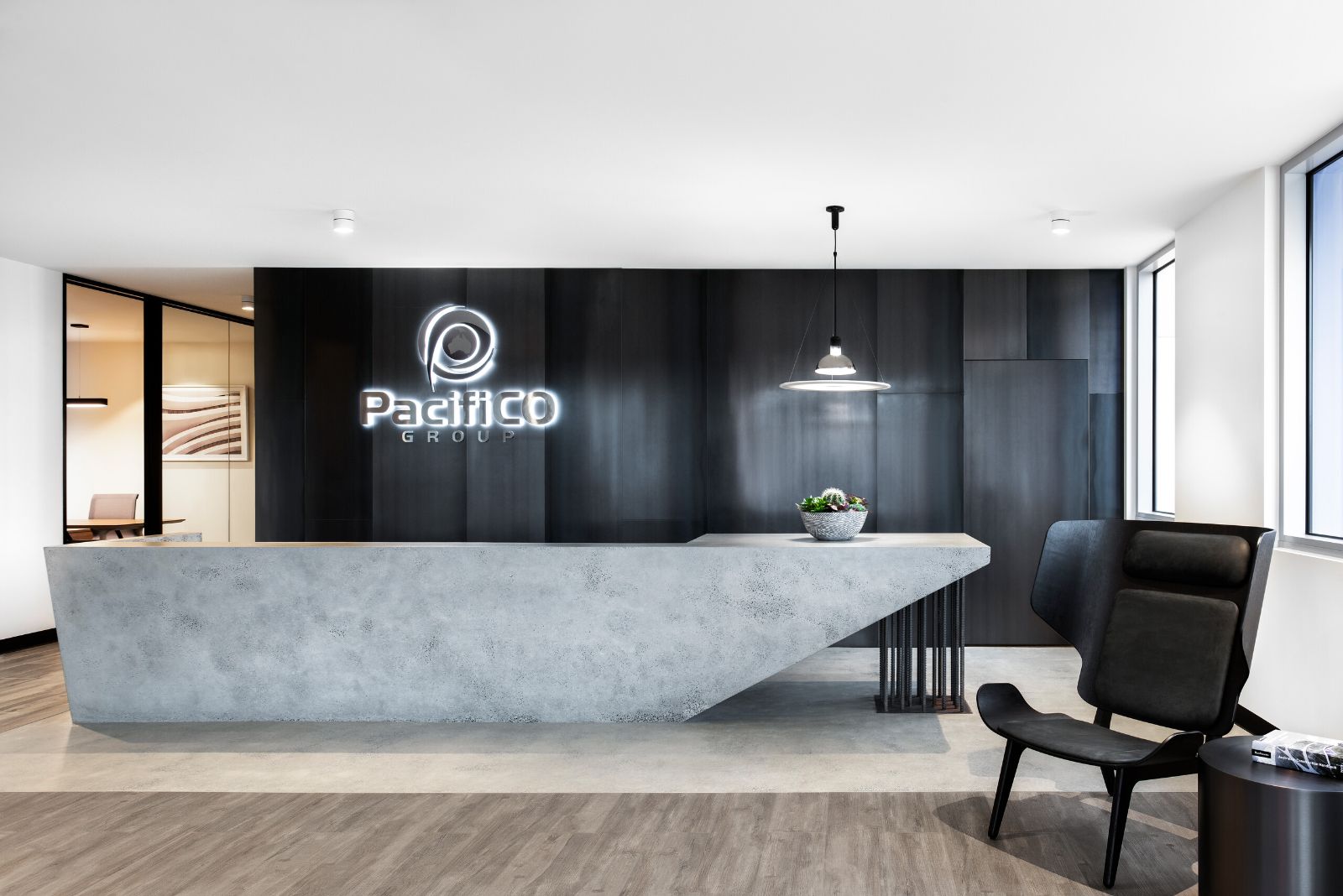PacifiCo Group reception with a concrete desk in front of a dark timber wall